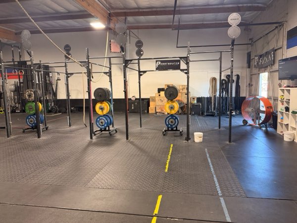 The pull-up rig under the PowerSource sign, with bumper plates and plyo boxes.