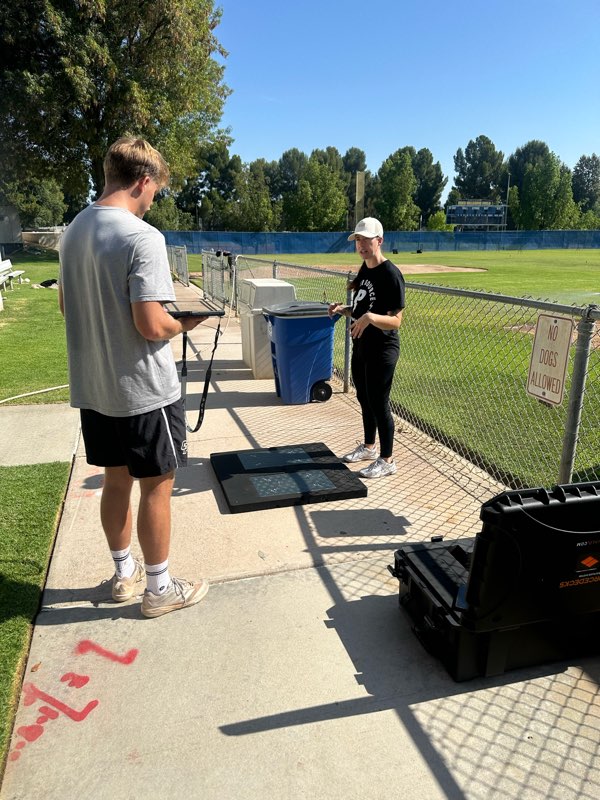 An athlete testing on force plates while a coach records the results.