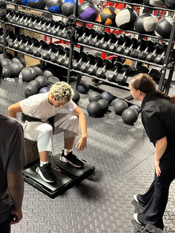 An athlete on the force plates while a coach watches.