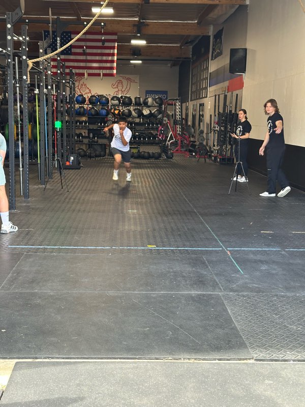 An athlete sprinting through the timing gates inside the gym.
