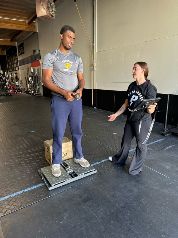 A coach setting up an athlete for an isometric pull on the force plates.