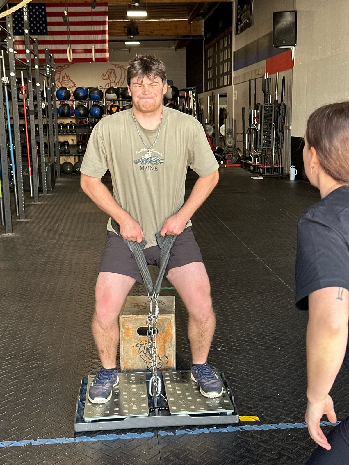 An athlete doing an isometric mid-thigh pull on the force plates while a coach watches.